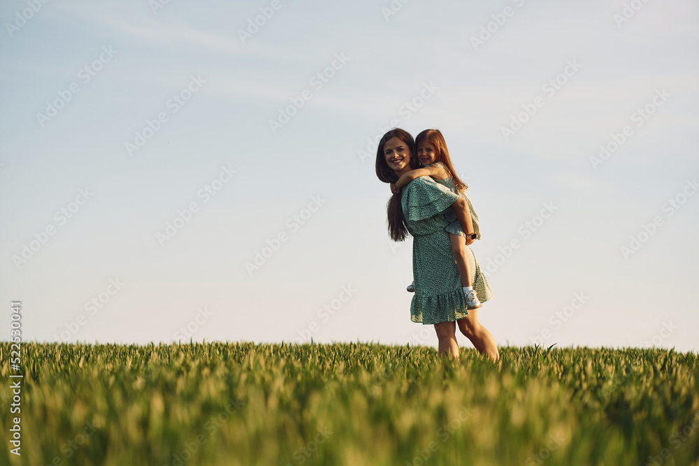 Clear sky. Mother and daughter have fun outdoors on the field at summer