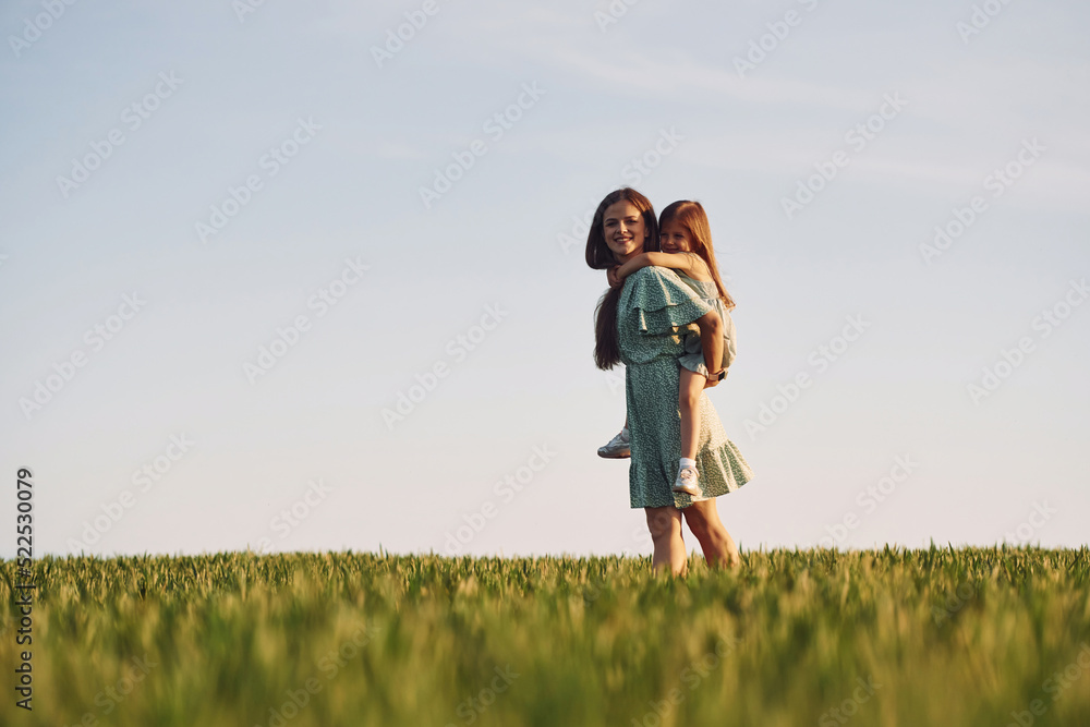 Clear sky. Mother and daughter have fun outdoors on the field at summer