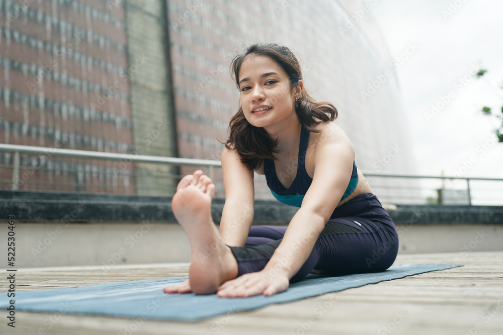 Young attractive woman doing stretching yoga exercise in the park.