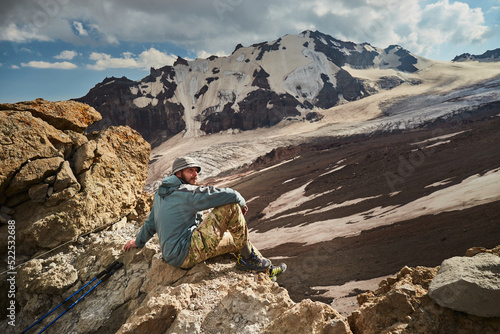 Man sitting over Mt Kazbeg base camp and enjoying view of Gergeti glacier. Meteostation in Kazbek, Georgia. Mount kazbek alpinist expedition