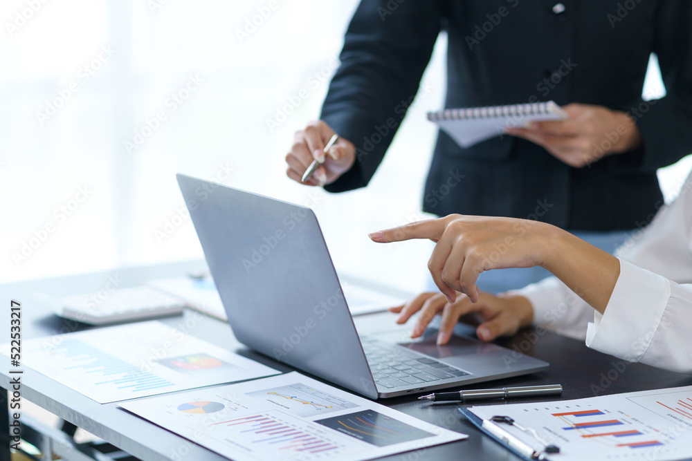 Close-up of a group of business people having a meeting Brainstorm together to come up with a plan for working on a laptop planning marketing strategies, analyzing balance sheets, income statements.