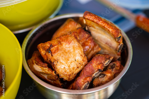 Close-up of fried pieces of pork ribs in a metal bowl. Food in nature. Small depth of field.