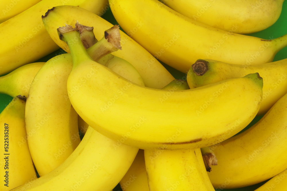 Many ripe bananas on green background