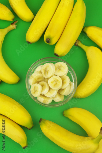 Whole and sliced bananas on green background.