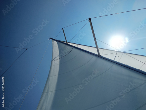 Bright sun over the sail on a background of blue sky