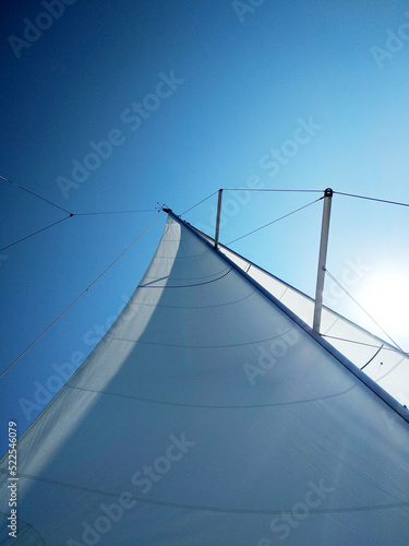 View of the bright sun over the yacht's sail on a clear summer day