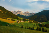 Stunning view of the Funes Valley (Val di Funes) with the Santa Maddalena Church and the mountain range of the Puez Odle Nature Park in the distance during a beautiful sunset. Santa Magdalena, Italy.