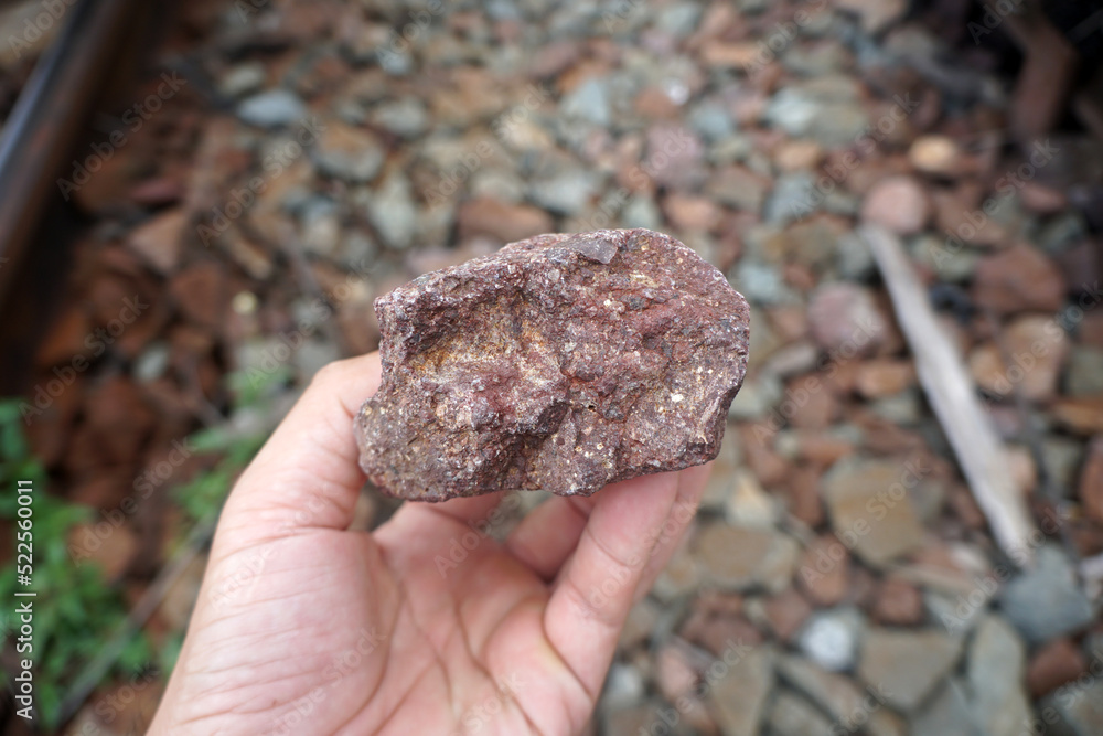 Sample of Rhyolite silicic volcanic rock stone on Geologist's hand. The paving stones are used to attach the rail to the rail sleepers. Sample of Rhyolite silicic volcanic rock stone on Geologist's hand. The paving stones are used to attach the rail to the rail sleepers.