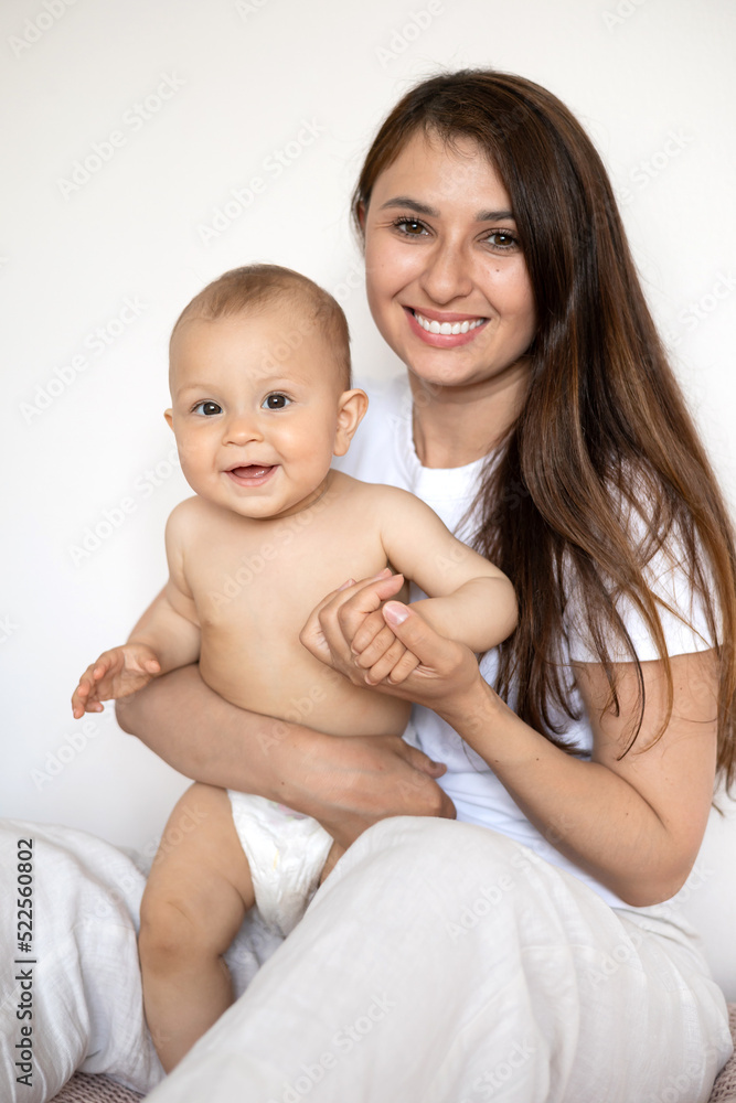 A portrait of a beautiful young mother and her sweet baby in a diaper. Motherhood. Happy family A portrait of a beautiful young mother and her sweet baby in a diaper. Motherhood. Happy family