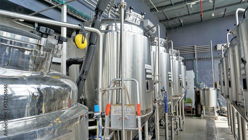Row of shiny metal micro brewery tanks or Fermentation mash vats in Brewery factory.