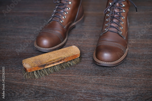 wooden shoe brush on wooden floor next to new leather boots