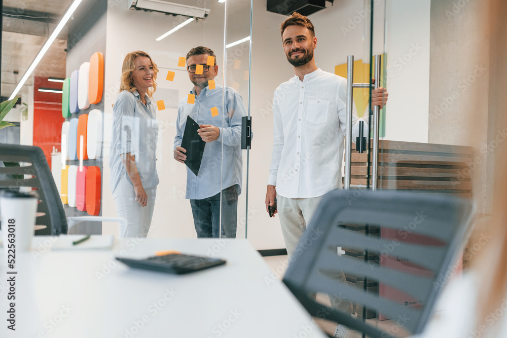 Three people standing together. Group of professional business people is in the office Three people standing together. Group of professional business people is in the office