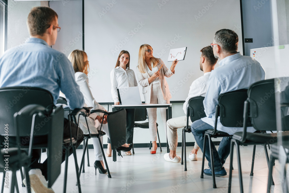 Sitting and learning new stuff from woman. Group of professional business people is in the office Sitting and learning new stuff from woman. Group of professional business people is in the office