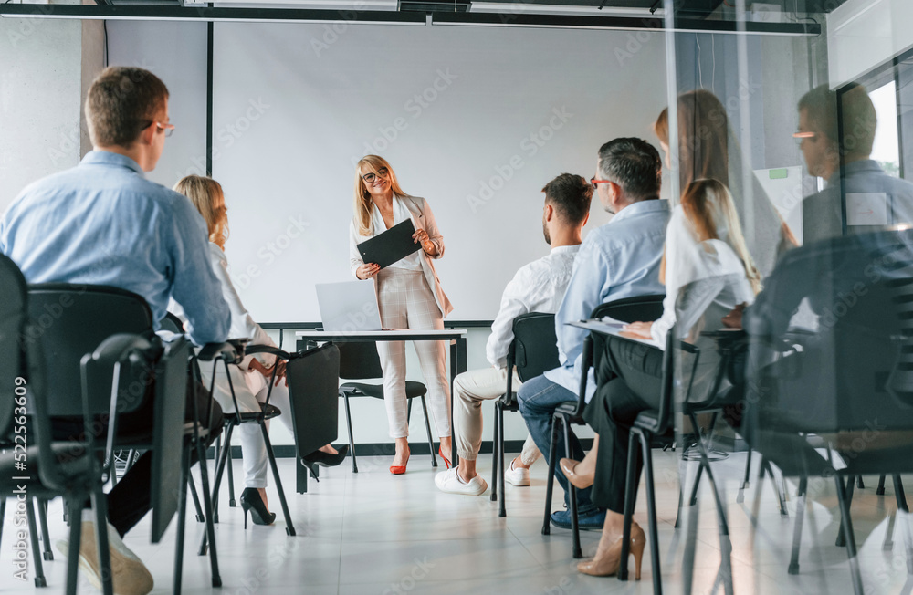 Sitting and learning new stuff from woman. Group of professional business people is in the office Sitting and learning new stuff from woman. Group of professional business people is in the office