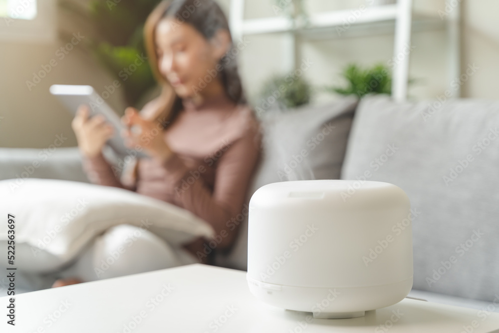 Air Humidifier Device At home and Woman relaxing on the sofa - obrazy, fototapety, plakaty 