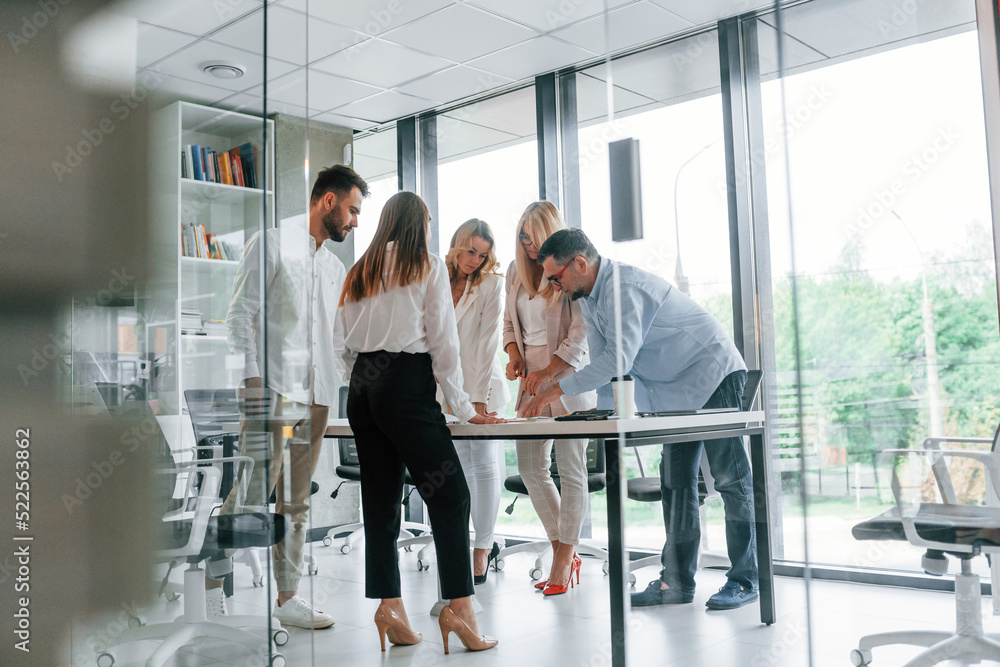 © standret - Standing by the table near big windows. Group of professional business people is in the office © standret - Standing by the table near big windows. Group of professional business people is in the office