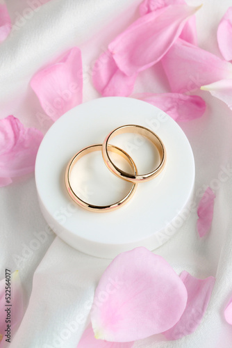 Two wedding gold rings and rose petals.
