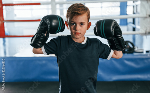 Boy is practicing boxing in the gym with glowes on hands © standret