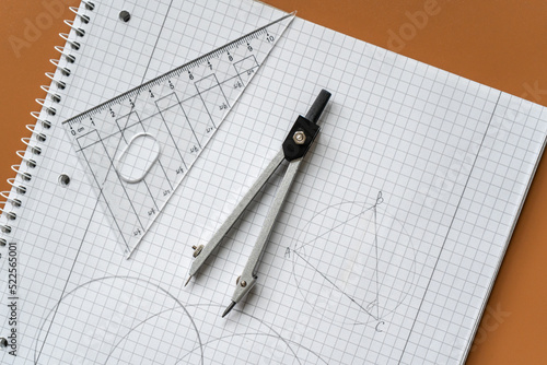 Close up Compass and ruler on the open notebook. Mathematical accessories, back to school background