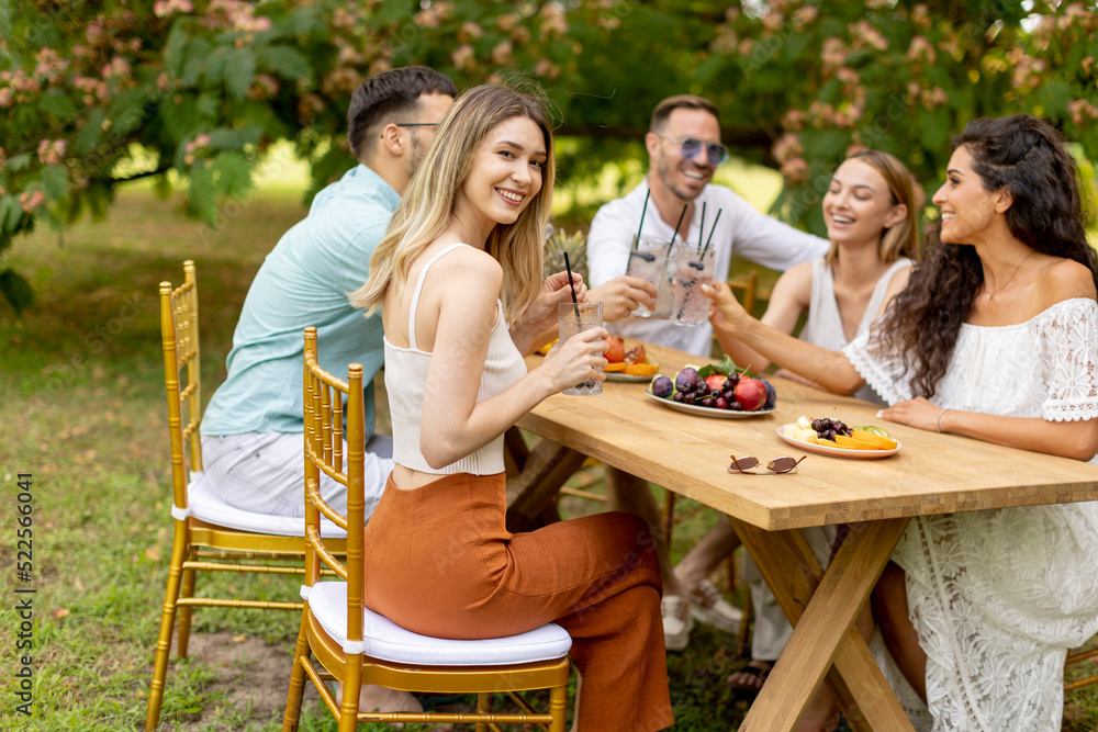 Group of happy young people cheering with fresh lemonade and eating fruits in the garden Group of happy young people cheering with fresh lemonade and eating fruits in the garden