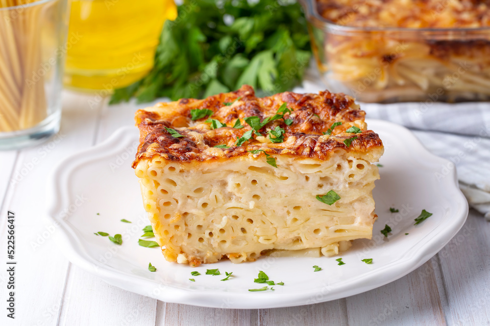 Pasta casserole bechamel sauce topped with melted mozzarella cheese and served in a white baking dish on a table (Turkish name; firinda makarna or firin makarna)