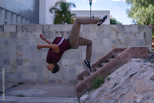 An athletic man doing a somersault in the air. Man in the middle of a jump backwards. Young man doing parkour.
