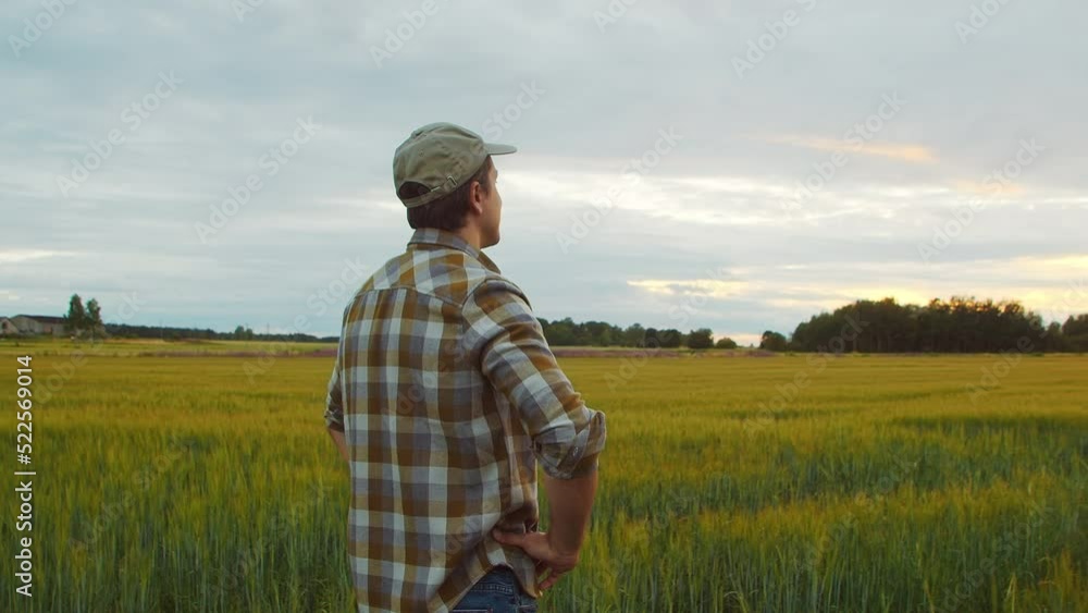 Farmer in front of a sunset agricultural landscape. Man in a countryside field. Country life, food production, farming and country lifestyle concept. Farmer in front of a sunset agricultural landscape. Man in a countryside field. Country life, food production, farming and country lifestyle concept.