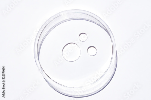 Transparent cosmetic face or body gel moisturizer drops on white background in petri dish. Hygiene, skincare product with jelly texture. Beauty face creme smear swatch on background.