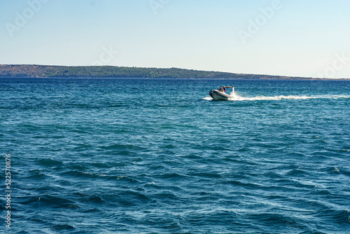 fast tourist boat rushes and leaves a white wake on the slightly agitated Adriatic sea, Croatia, summer, afternoon