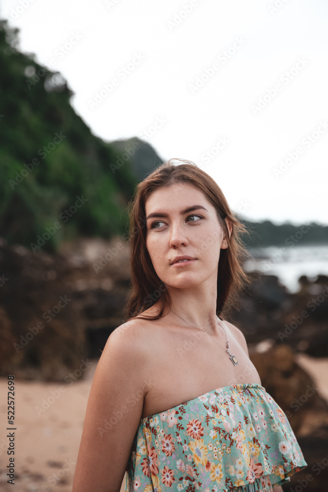 Young woman in dress walking alone on the beach in tropical nature