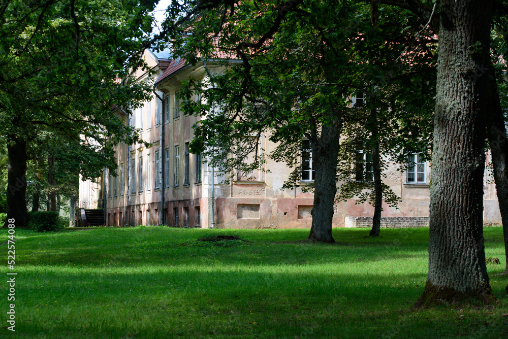 outdoor park with green grass ancient buildings and old oak trees in the distance in sunny weather outdoor park with green grass ancient buildings and old oak trees in the distance in sunny weather