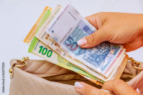 A woman takes kunas and euros from her purse on a white background. Tourism and currency exchange. photo