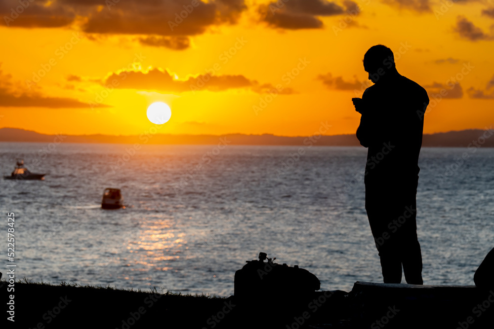 Fototapeta premium Hoem no por do sol com celular na mão