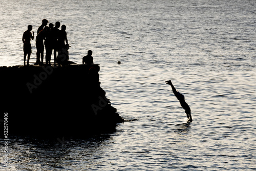 meninos mergulhando do dique na praia do porto em salvador photo