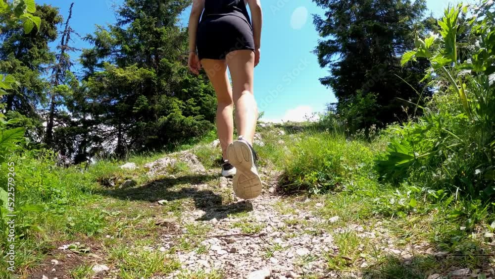 A woman walks down a rocky road in sneakers. Hiking in the mountains. A woman walks down a rocky road in sneakers. Hiking in the mountains.