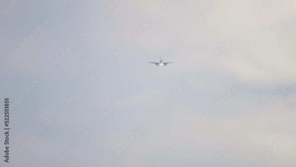 Long shot of passenger jet approaching for landing against a cloudy gray sky. Tourism and aviation concept Long shot of passenger jet approaching for landing against a cloudy gray sky. Tourism and aviation concept