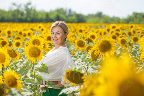 Happy beautiful blonde woman in sunflowers field