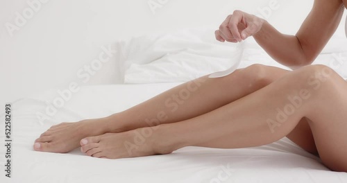 Closeup of female hand touching perfect hairless soft and silky skin with white feather