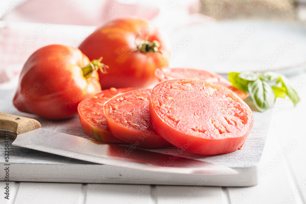 Sliced bull heart tomatoes on cutting board.