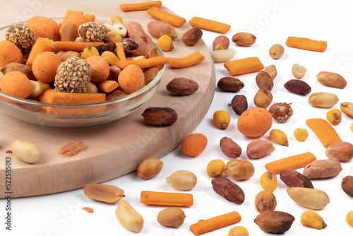 Mixed roasted nuts and peanuts peeled in a glass bowl, against a wooden board. Close up view.