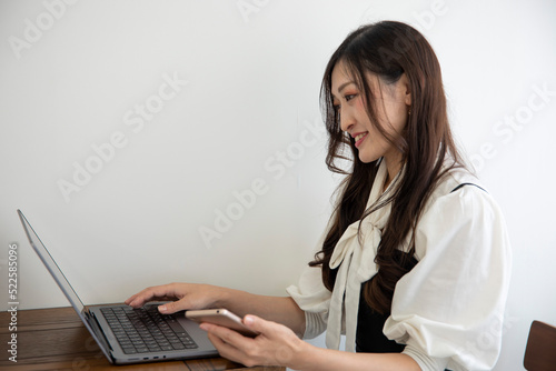 A Japanese woman checking smartphone by remote work in the small office
