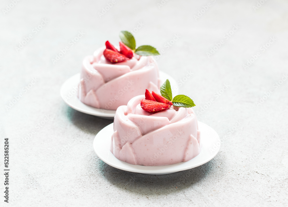 Strawberry cream pudding, Panna Cotta, in the shape of a rose, on a plate. Light grey background