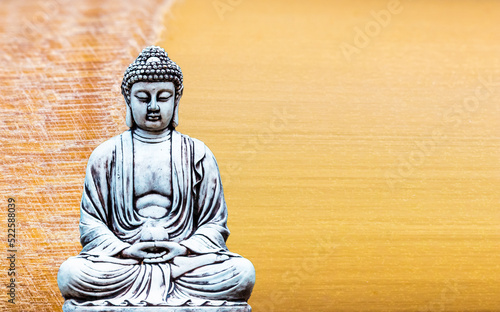 Buddha statue sitting in meditation and bamboo textured background.