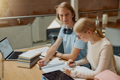 Two talented students working together on university project sitting in library