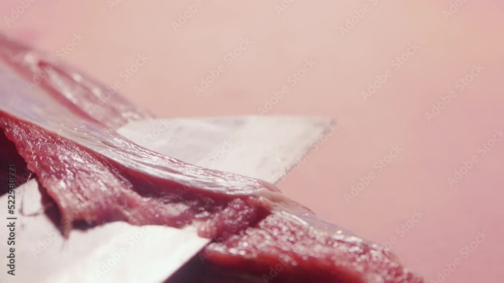 Chef cuts off connective tissue and surface membrane from a raw beef