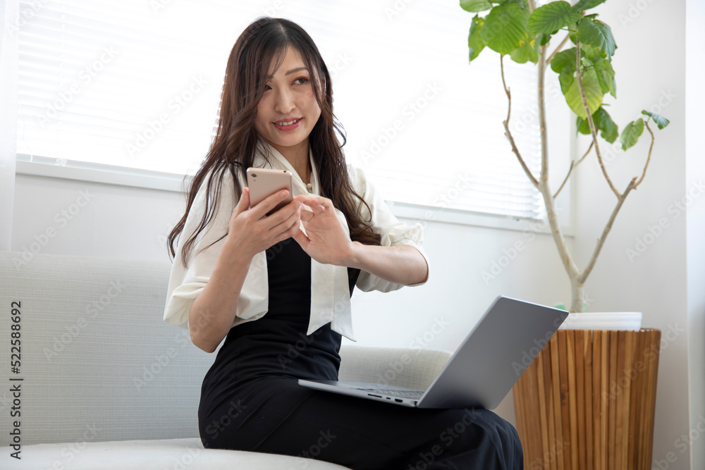 A Japanese woman checking smartphone by remote work in the small office A Japanese woman checking smartphone by remote work in the small office