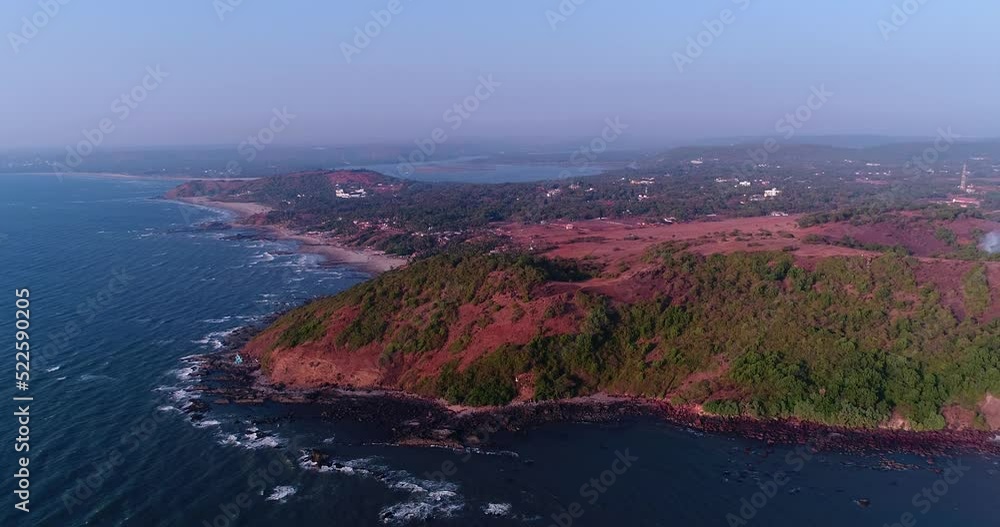 Aerial shot of coast with red soil, some bushes over it and rocky beach Aerial shot of coast with red soil, some bushes over it and rocky beach