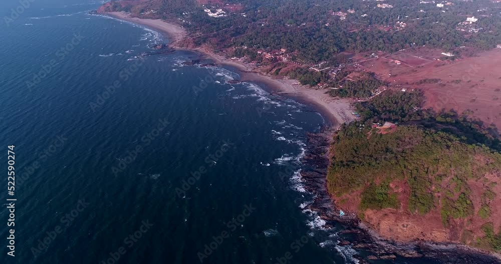 Aerial shot of coast with red soil, buildings along it and rocky beach Aerial shot of coast with red soil, buildings along it and rocky beach