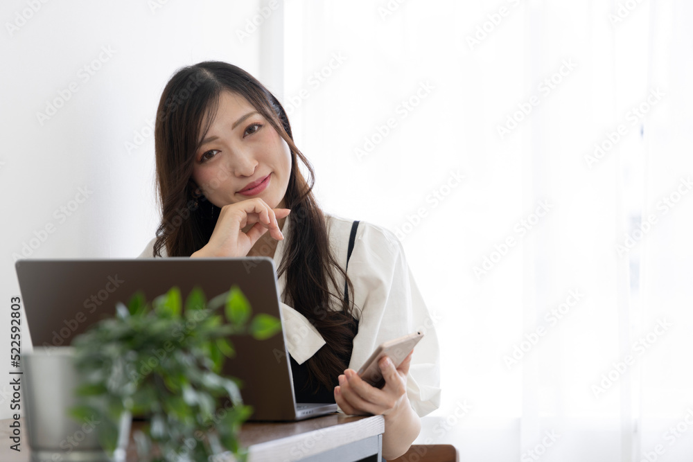 A Japanese woman checking smartphone by remote work in the small office