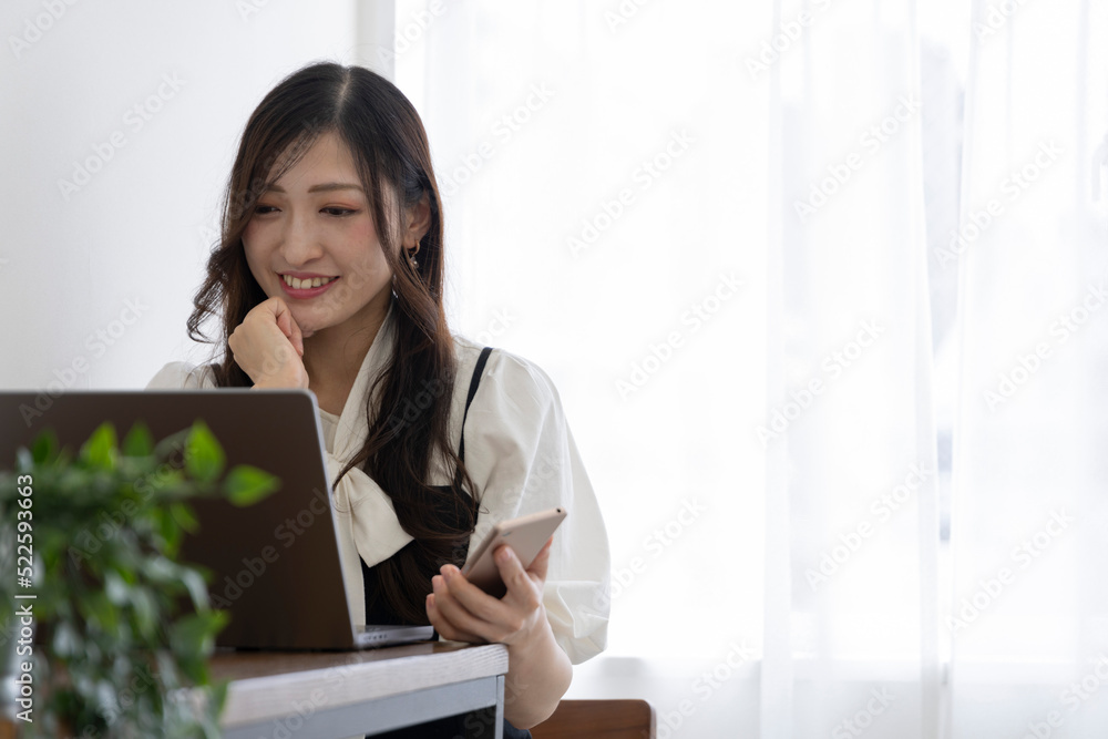 A Japanese woman checking smartphone by remote work in the small office